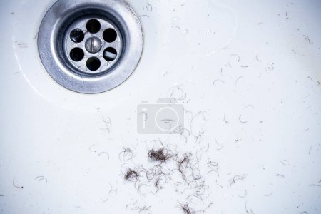 cabello afeitado de las zonas íntimas de la zona púbica después del afeitado y depilación restante en las paredes del lavabo del baño, textura de primer plano