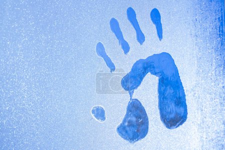 Téléchargez les photos : Empreintes de mains et de pieds sur verre glacé en contre-jour, durcissement dans la neige pour aider à restaurer la santé - en image libre de droit