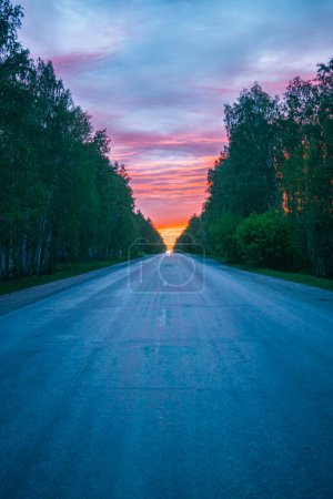 route au coucher du soleil rouge dans une forêt