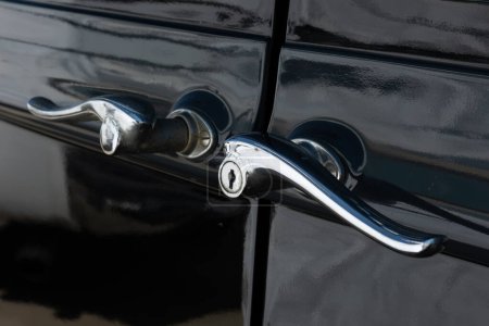 Téléchargez les photos : Un gros plan de poignées de porte suicide ornées sur voiture noire vintage. - en image libre de droit