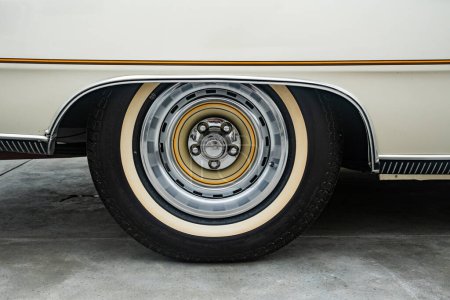 Foto de Vista de cerca de la rueda de coche americana vintage de 1970 con neumáticos clásicos de pared blanca. - Imagen libre de derechos