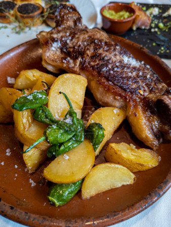Photo for Typical Spanish dish called beef entrecote with padron peppers and baked potatoes - Royalty Free Image