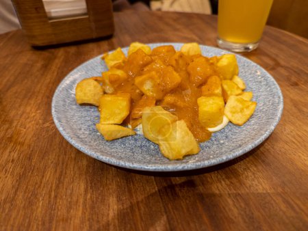 Photo for Typical Spanish dish called patatas bravas, fried tubers with red spicy sauce containing onion, paprika, oregano, chilli - Royalty Free Image