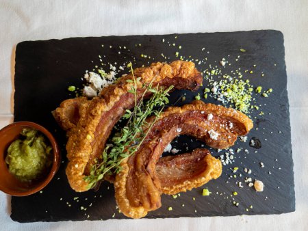 Photo for Gourmet, Typical Spanish dish called torreznos, consisting of deep-fried pork skin and savory fried crust - Royalty Free Image