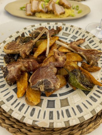 Foto de Chuletas de cordero con papas fritas en plato blanco con chiles verdes. Plato típico castellano en España - Imagen libre de derechos