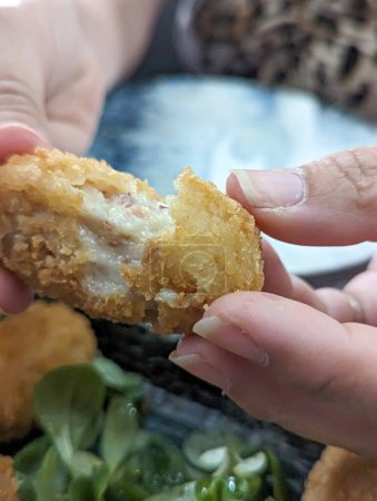 Photo for Gourmet Revelation: Intriguing Moment Captured as a Person Unwraps a Croquette, Exposing the Succulent Combination of Jam and Creamy Melted Cheese, a Mouthwatering Exploration of Culinary Craftsmanship - Royalty Free Image