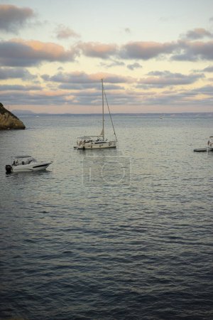 Foto de Al atardecer, barcos de recreo anclan en una pintoresca cala de Mallorca, reflejando la belleza y el encanto del paraíso costero español. - Imagen libre de derechos