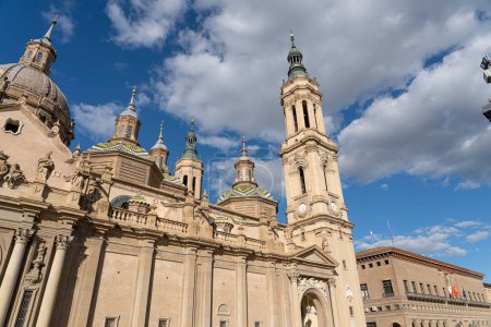 Foto de Gran vista frontal de la fachada barroca de la Basílica del Pilar, adornada con esculturas, bajo un cielo azul vibrante - Imagen libre de derechos