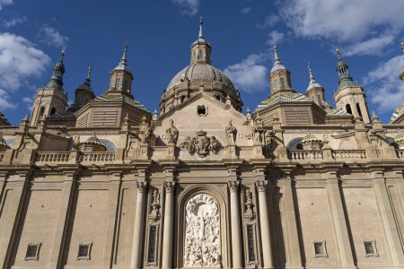 Grand front view of Basilica del Pilar's Baroque facade, adorned with sculptures, under a vibrant blue sky