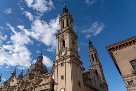 Close-up of the Basilica del Pilar's clock tower, a fusion of historical and functional architecture against a serene sky.