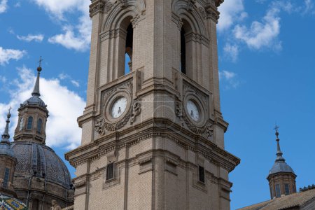 Close-up of the Basilica del Pilar's clock tower, a fusion of historical and functional architecture against a serene sky.