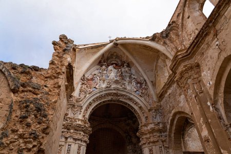 Eine vertikale Aufnahme, die die komplizierte Fassade der verwitterten Ruinen der Kirche Monasterio de Piedra vor wolkenverhangenem Himmel einfängt.