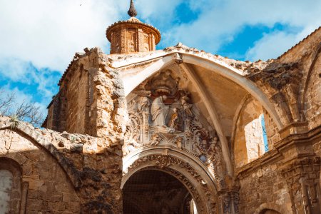 Foto de Un disparo vertical que captura la intrincada fachada de las ruinas erosionadas de la iglesia del Monasterio de Piedra contra un cielo nublado. - Imagen libre de derechos
