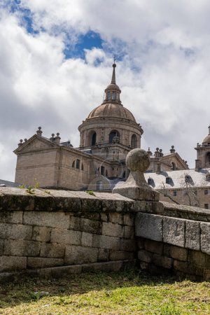 Téléchargez les photos : Le grand dôme du monastère Escorial près de Madrid, en Espagne, s'élève majestueusement sur fond de nuages dynamiques. - en image libre de droit