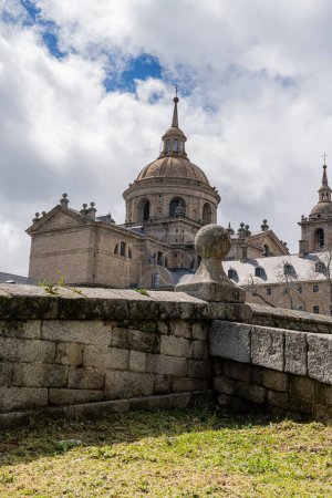 The grand dome of the Escorial Monastery near Madrid, Spain, rises majestically against a backdrop of dynamic clouds.