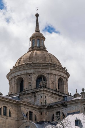 La gran cúpula del Monasterio Escorial cerca de Madrid, España, se eleva majestuosamente sobre un telón de fondo de nubes dinámicas.