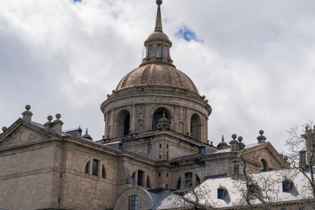 Téléchargez les photos : Le grand dôme du monastère Escorial près de Madrid, en Espagne, s'élève majestueusement sur fond de nuages dynamiques. - en image libre de droit