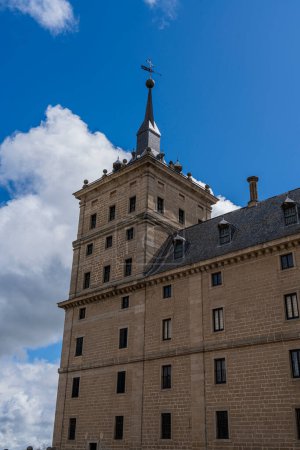 Téléchargez les photos : Les détails sculpturaux et le dôme emblématique du monastère El Escorial se distinguent par un ciel bleu avec des nuages duveteux - en image libre de droit