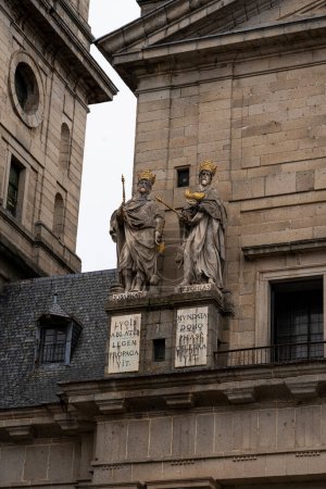Téléchargez les photos : Des statues dorées de rois bibliques ornent la façade du monastère El Escorial, dressées contre les murs pierreux et les plaques inscrites. - en image libre de droit