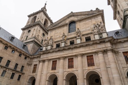 Téléchargez les photos : Des statues de personnages historiques se dressent sur la cour principale du monastère El Escorial, contre l'élégance austère de la façade du bâtiment. - en image libre de droit