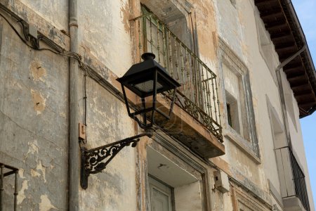 Photo for An old street lamp hangs from a building with peeling paint, highlighting the rustic charm of urban decay. - Royalty Free Image