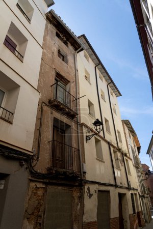 Téléchargez les photos : Gros plan d'un balcon antique avec des balustrades ornées sur un bâtiment urbain vieillissant aux murs en détresse - en image libre de droit