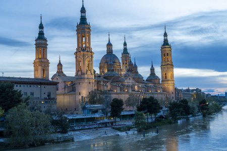Foto de Vista del crepúsculo de la Basílica de Nuestra Seora del Pilar junto al río Ebro en Zaragoza, con improntas iluminadas. - Imagen libre de derechos