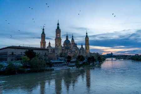 Foto de Vista del crepúsculo de la Basílica de Nuestra Seora del Pilar junto al río Ebro en Zaragoza, con improntas iluminadas. - Imagen libre de derechos