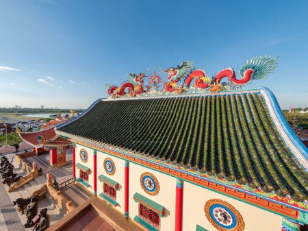 Téléchargez les photos : Bâtiment avec des dragons de style chinois sur le toit à Viharn Sien, un musée et sanctuaire chinois-thaïlandais près de Wat Yan à Huai Yai, près de Pattaya, province de Chonburi en Thaïlande. L'horizon de la plage de Jomtien visible à l'horizon. - en image libre de droit