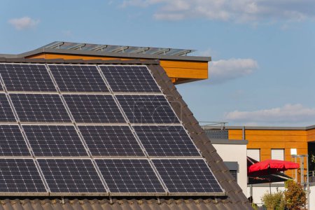 Téléchargez les photos : Toit de panneau solaire sur le toit de construction dans la ville allemande du sud avec ciel bleu et soleil sur les plantes vertes - en image libre de droit
