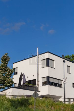 Téléchargez les photos : Maison moderne façade avec cheminée fenêtres balcon sur ciel bleu en Allemagne du sud jour d'été - en image libre de droit