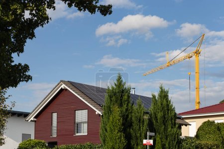 Foto de Edificio prefabricado frente a la construcción de madera con paneles solares en la azotea en el sur de Alemania y grúa de construcción - Imagen libre de derechos