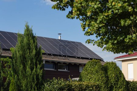 Foto de Nuevo edificio con panel solar en la azotea y jardín arbusto de árbol verde en el sur de Alemania verano cielo azul día - Imagen libre de derechos