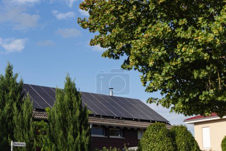 Foto de Nuevo edificio con panel solar en la azotea y jardín arbusto de árbol verde en el sur de Alemania verano cielo azul día - Imagen libre de derechos