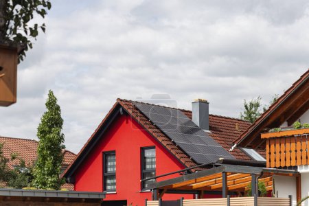 Foto de Nuevo edificio con panel solar en la azotea y fachada de casa roja con cielo nublado en el sur de Alemania nueva área de construcción - Imagen libre de derechos