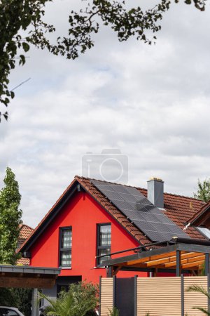Téléchargez les photos : Nouveau bâtiment avec panneau solaire sur le toit et la façade de la maison rouge avec ciel nuageux dans le sud de l'Allemagne nouvelle zone de construction - en image libre de droit