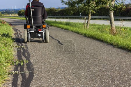 Téléchargez les photos : Fauteuil roulant avec moteur à côté d'une route en été en Allemagne - en image libre de droit