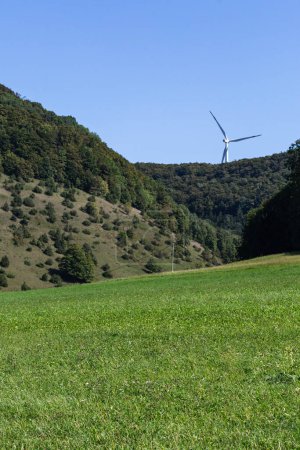 Photo for Wind turbine in natural landscape environment near green forest and agricultural area - Royalty Free Image