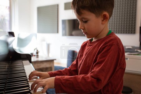 Téléchargez les photos : Beau jeune garçon apprenant à jouer du piano seul - en image libre de droit