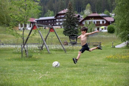 Téléchargez les photos : Beau jeune garçon jouant au football sur une prairie - en image libre de droit