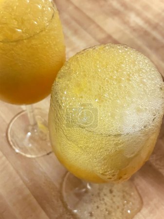 Foto de Dos grandes copas de cóctel en una encimera, repletas de burbujas de champán y zumo de naranja, listas para disfrutar. - Imagen libre de derechos