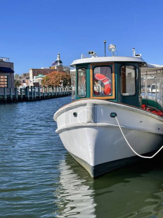 Foto de Un pequeño y hermoso barco de alquiler verde y blanco está amarrado en un muelle en una soleada mañana de otoño en el puerto en el centro de Annapolis, Maryland. - Imagen libre de derechos