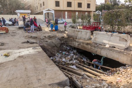 Photo for CAIRO, EGYPT - JANUARY 30, 2019: Rubbish in a water canal in Giza neighborhood of Cairo, Egypt - Royalty Free Image