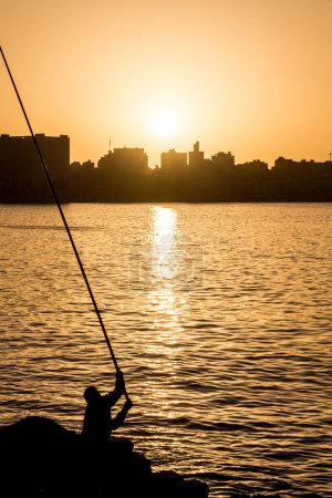 Téléchargez les photos : Silhouette of a fisherman and a skyline of Alexandria, Egypt - en image libre de droit