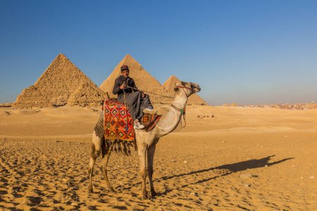 Photo for CAIRO, EGYPT - JANUARY 28, 2019: Camel rider in front of the Great pyramids of Giza, Egypt - Royalty Free Image