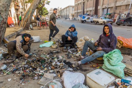 Foto de ALEXANDRIA, EGYPT - FEBRUARY 2, 2019: Young man dismantling old electronics on a street in Alexandria, Egypt - Imagen libre de derechos
