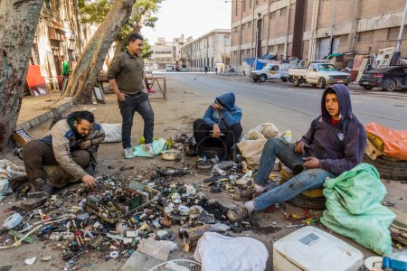 Téléchargez les photos : ALEXANDRIA, EGYPT - FEBRUARY 2, 2019: Young man dismantling old electronics on a street in Alexandria, Egypt - en image libre de droit