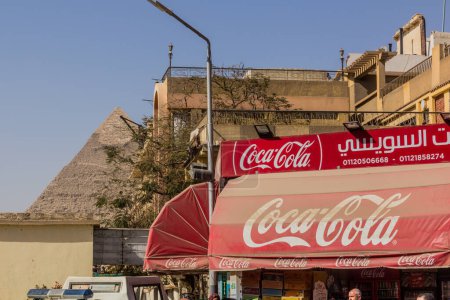 Foto de CAIRO, EGYPT - JANUARY 31, 2019: View of the Pyramid of Khafre and a Coca Cola sign in Giza neighborhood of Cairo, Egypt - Imagen libre de derechos