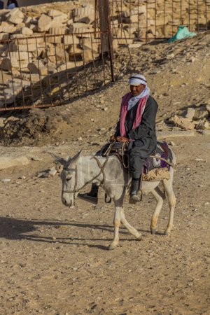 Téléchargez les photos : SAQQARA, EGYPT - JANUARY 31, 2019: Local man riding a  donkey at the Djoser (Zoser) funerary complex in Saqqara, Egypt - en image libre de droit