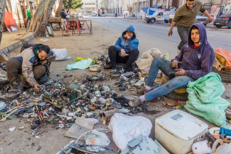 Photo for ALEXANDRIA, EGYPT - FEBRUARY 2, 2019: Young man dismantling old electronics on a street in Alexandria, Egypt - Royalty Free Image